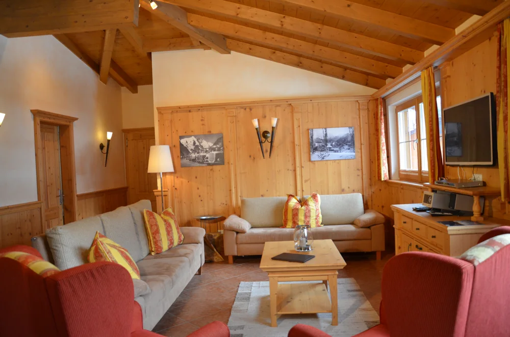 Wohnzimmer im Penthouse Kitzpanorama mit alpinem Holzinterieur und gemütlichen Sitzmöbeln